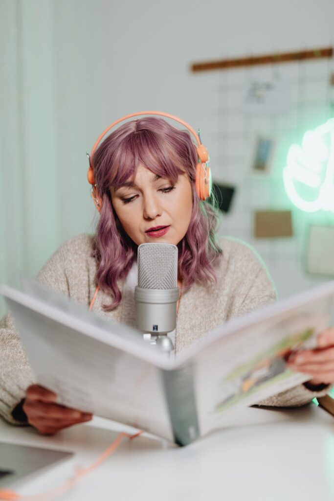 a woman talking on a microphone while reading a book